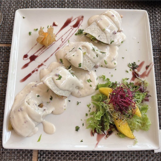 un plato de comida con salsa blanca y ensalada