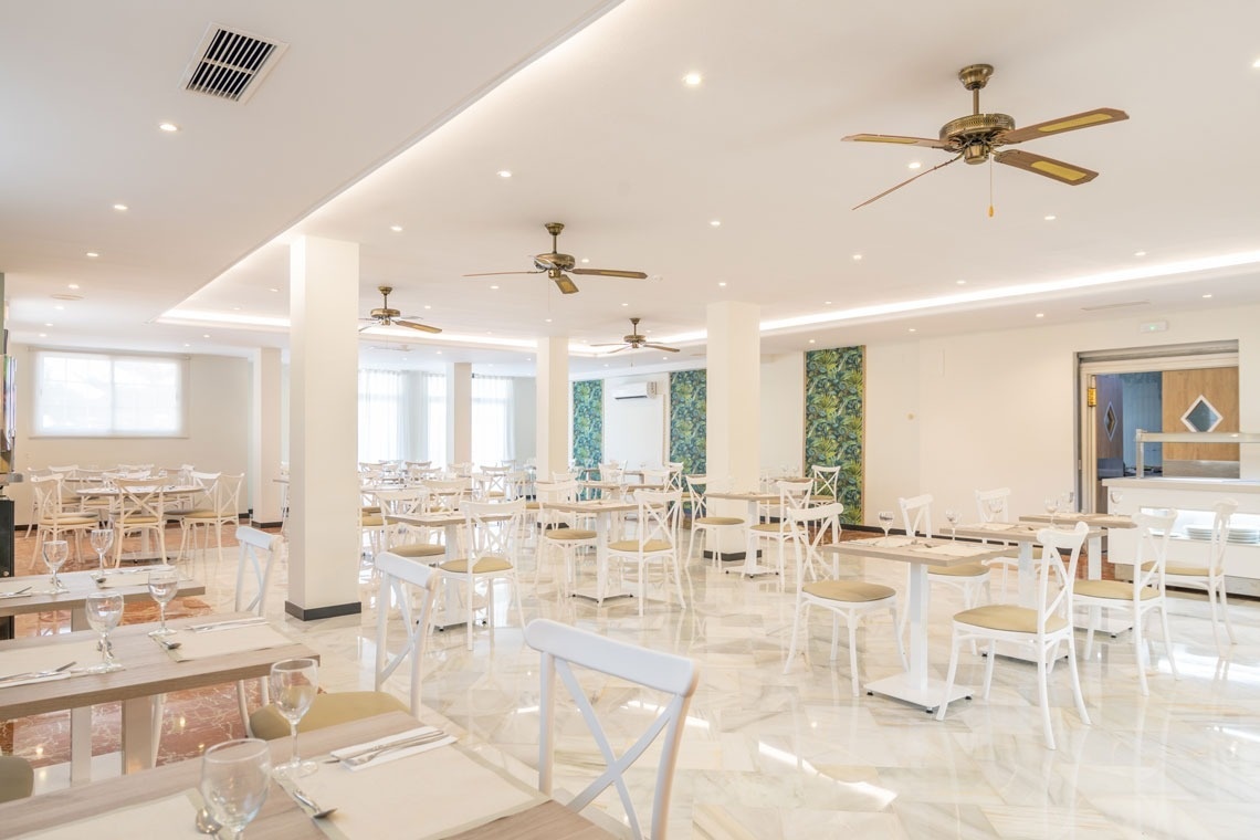 un comedor lleno de mesas y sillas con ventiladores de techo
