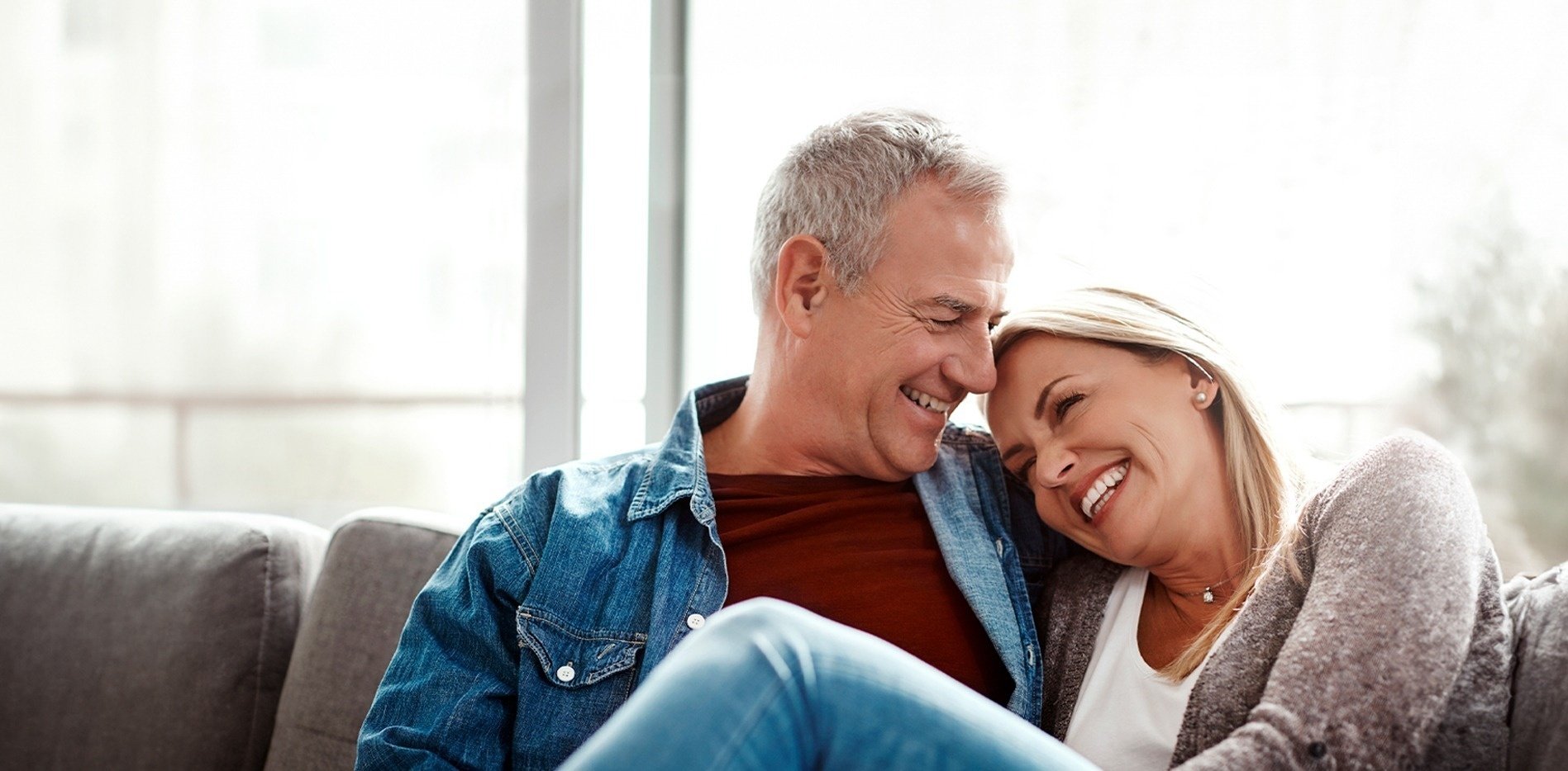 un hombre y una mujer están sentados en un sofá mirándose y sonriendo