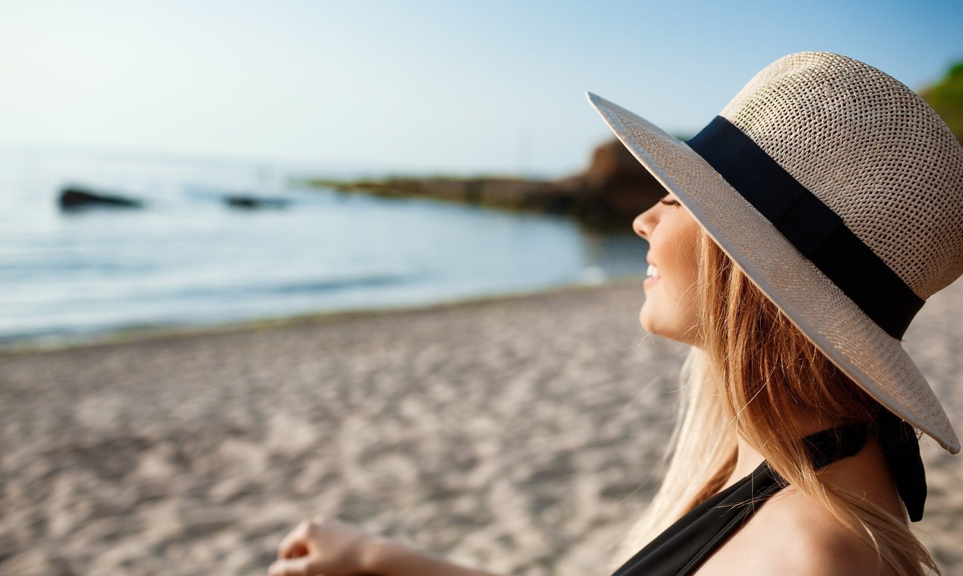 a woman wearing a straw hat is laying on the beach