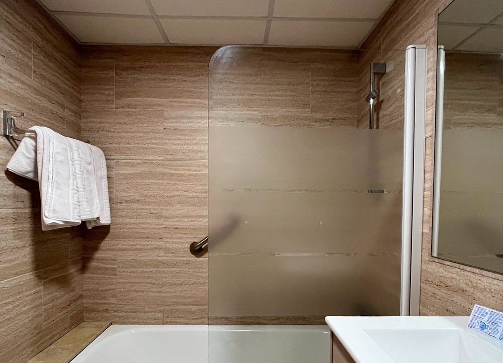 un baño con una bañera y una puerta de ducha de vidrio