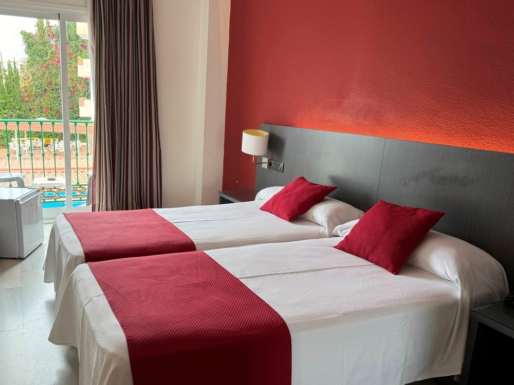 a hotel room with two beds and a red wall