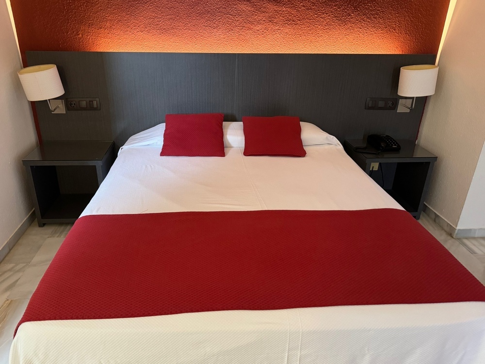 a bed with a red blanket and two red pillows