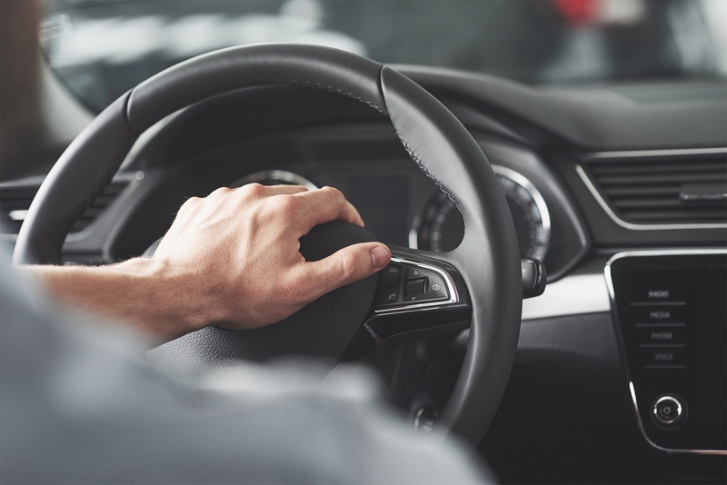 un hombre presiona un botón en el volante de un coche
