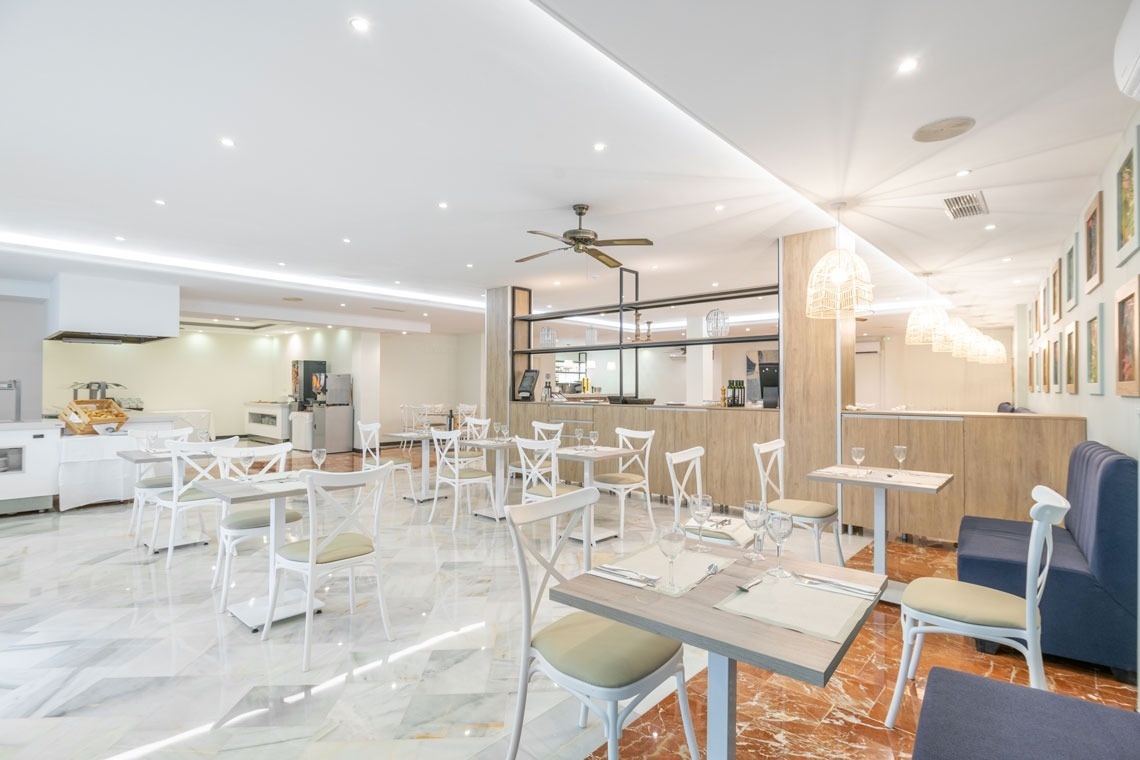 un restaurante con mesas y sillas blancas y un ventilador de techo