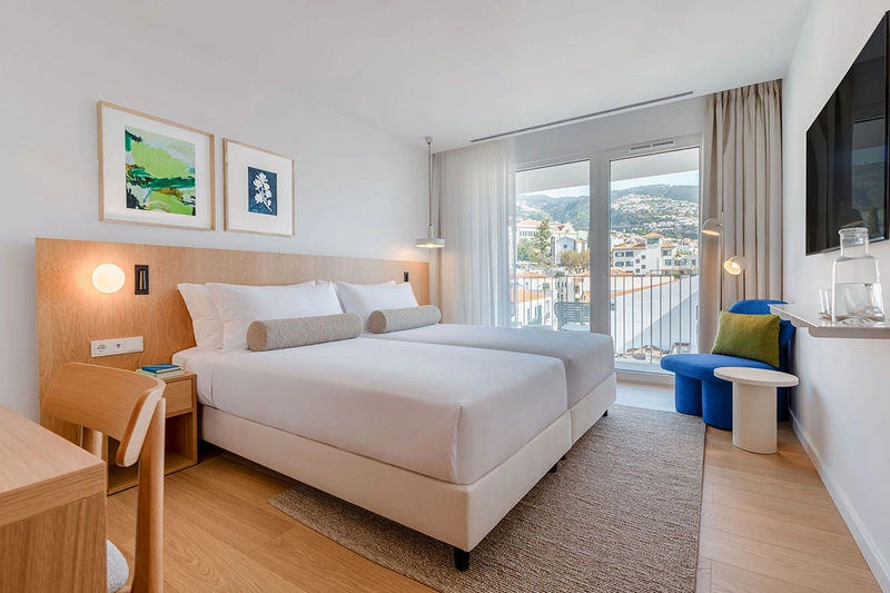 Quarto de hotel Orquídea com cama, secretária e varanda.