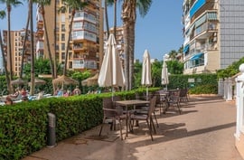 un patio con mesas y sillas y paraguas frente a un edificio