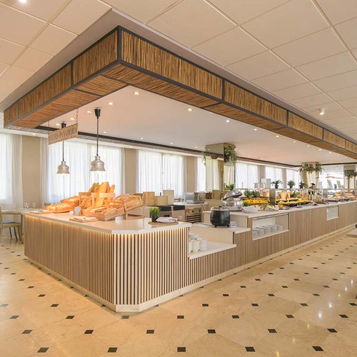 Imagen de un moderno restaurante buffet con un extenso mostrador de comida, decoración de bambú y un distintivo suelo de baldosas.