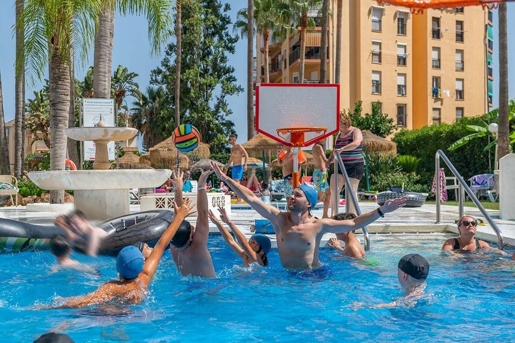 Amusement à la piscine de l'hôtel: basket aquatique en famille sous les palmiers.
