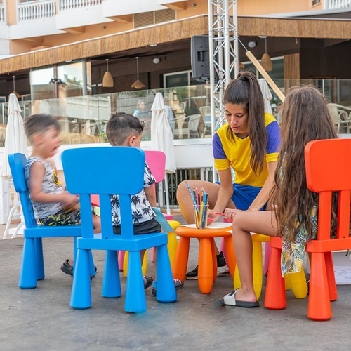 a woman in a yellow shirt sits at a table with children