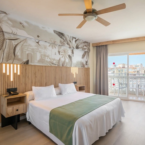 a hotel room with a large bed and a ceiling fan