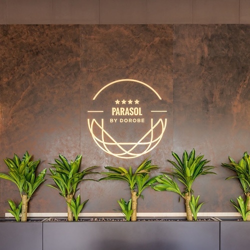 una pared marrón con plantas y un logotipo parasol por dorobe