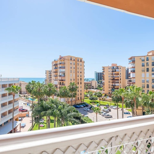 a view of a city from a balcony with palm trees in the foreground