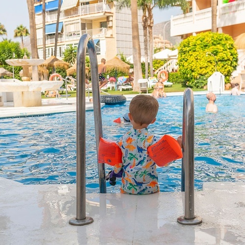 a young boy wearing arm bands is getting out of a swimming pool