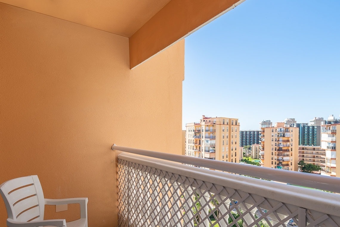 un balcón con una silla blanca y un edificio en el fondo