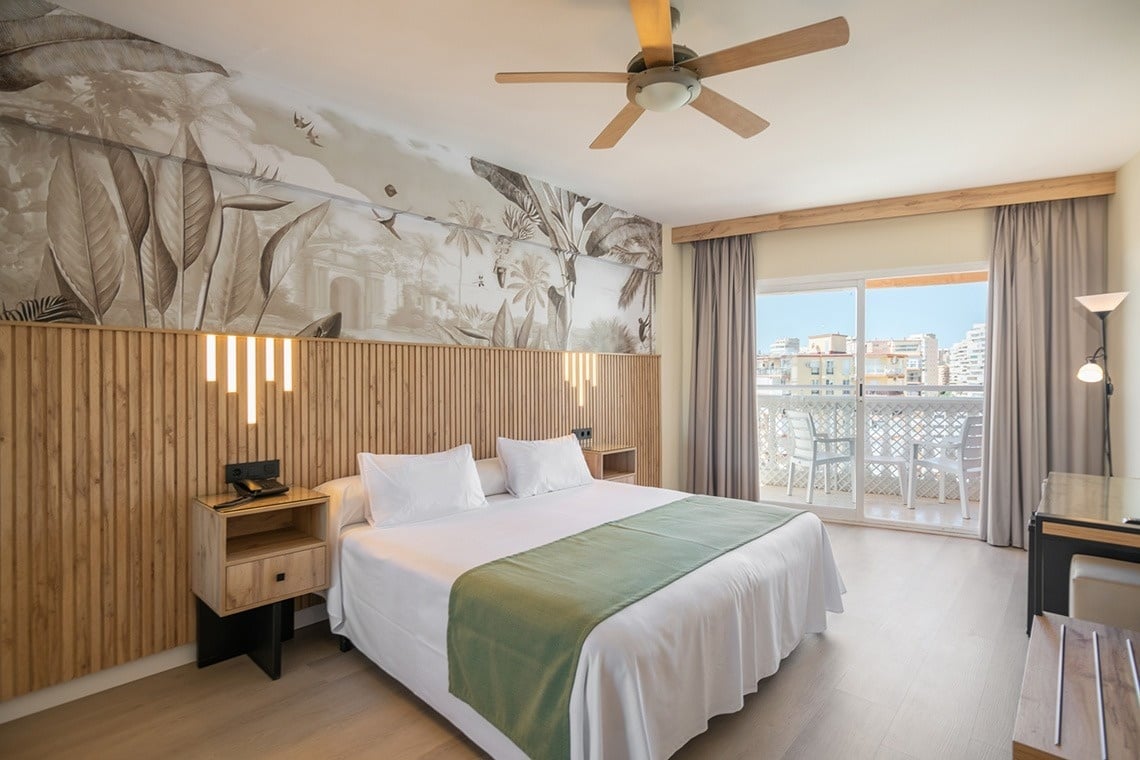 a hotel room with a large bed and a ceiling fan