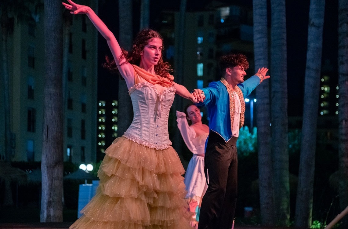 a man in a blue jacket is dancing with a woman in a white dress