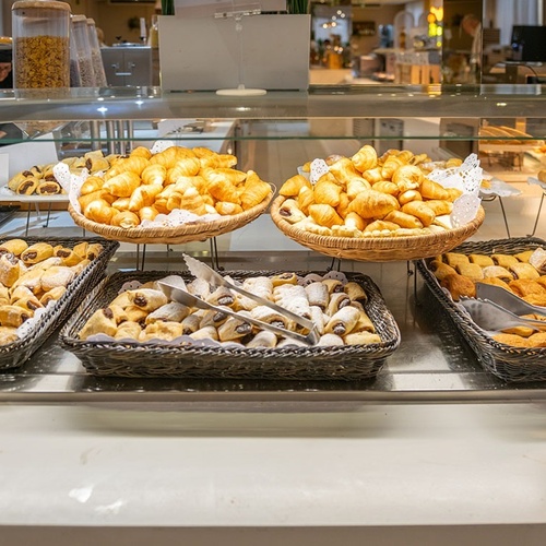 a display of pastries including croissants and pastries with tongs