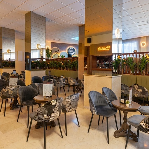 a restaurant with tables and chairs and a sign that says ' stella artois ' on it