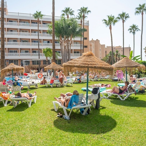 a group of people laying on lawn chairs under straw umbrellas