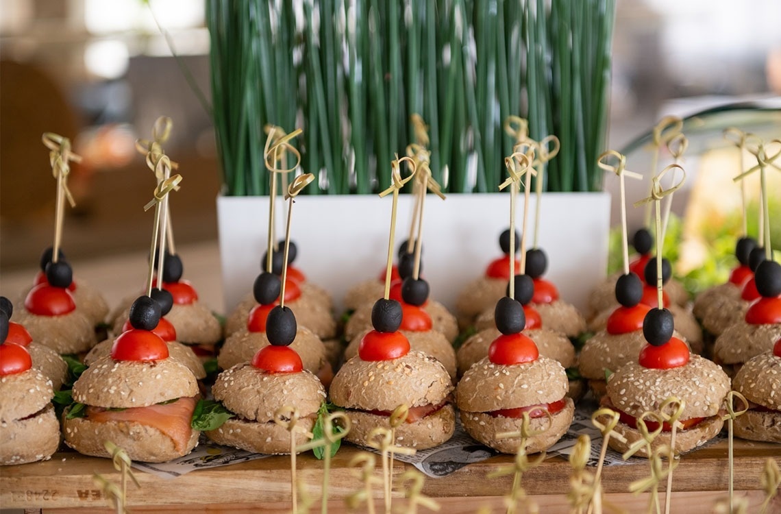 un montón de sándwiches con tomates y aceitunas en palos