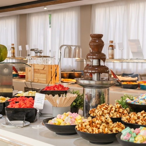 un buffet con una fuente de chocolate y varios platos de comida