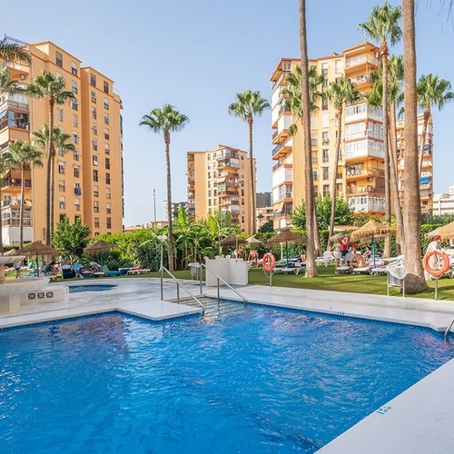 a large swimming pool surrounded by palm trees and buildings