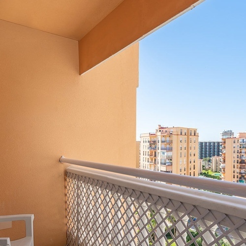 un balcón con una silla blanca y un edificio en el fondo