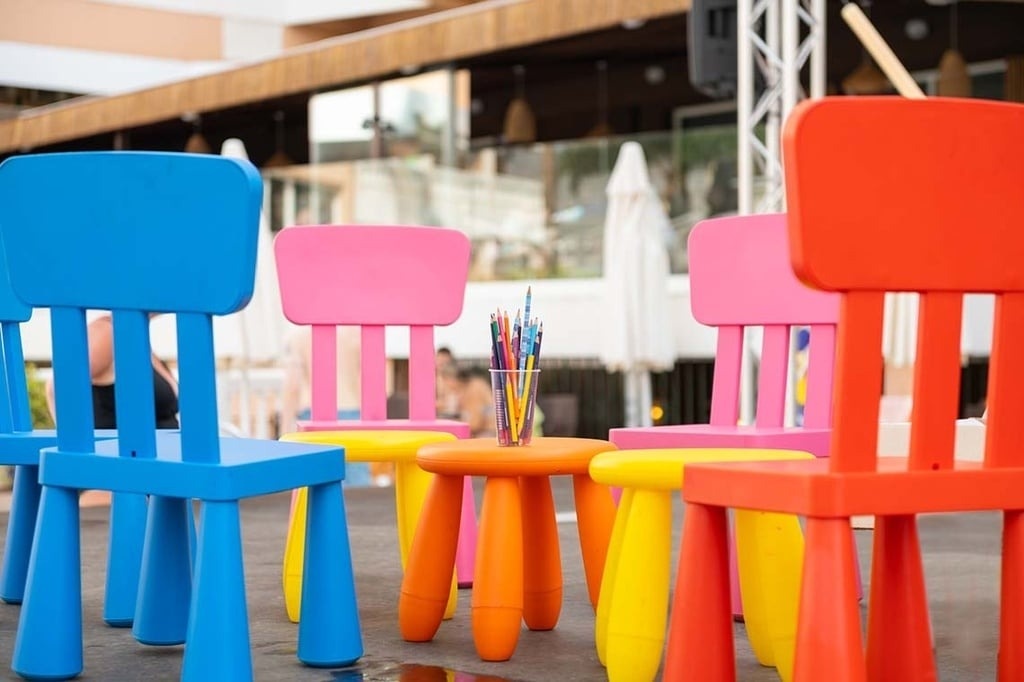 Espace enfants extérieur d'hôtel: chaises et table colorées avec crayons de couleur.
