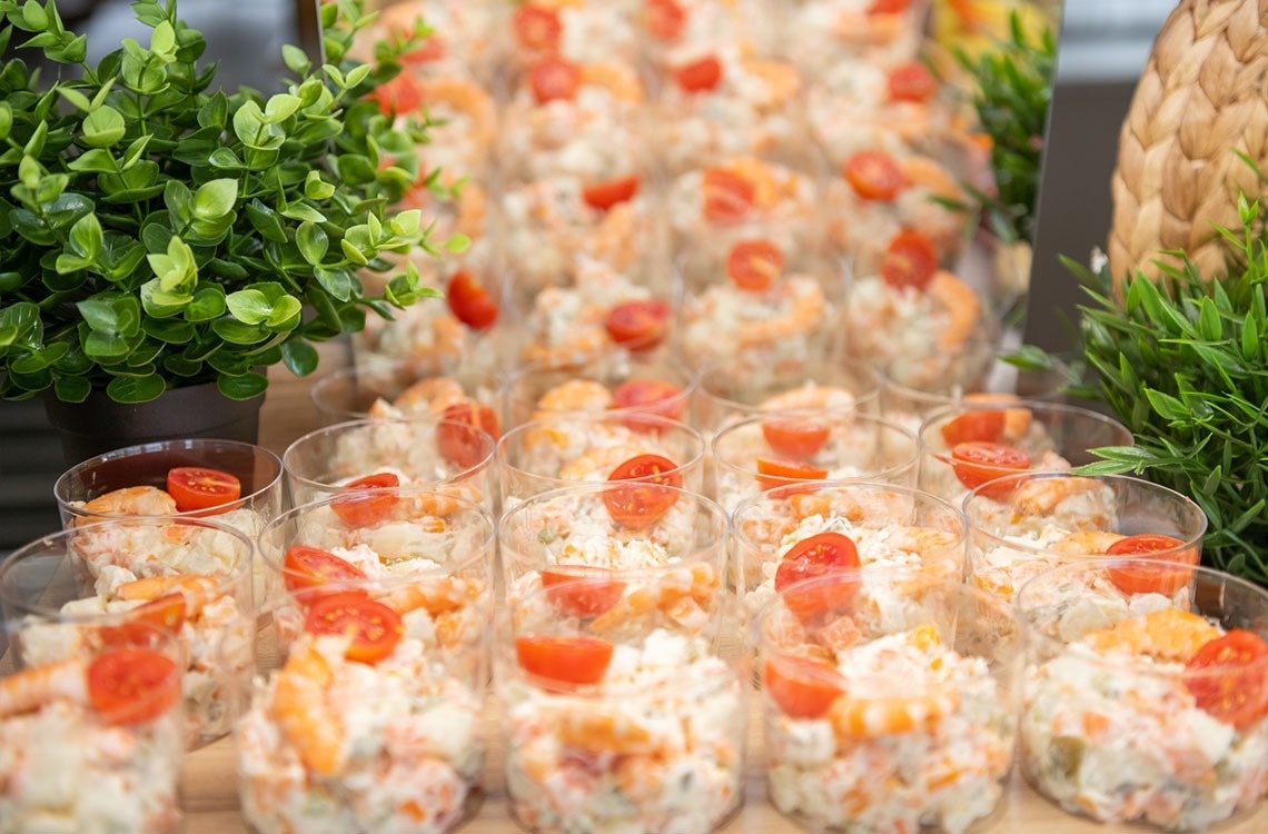 a display of salads with shrimp and tomatoes in plastic cups