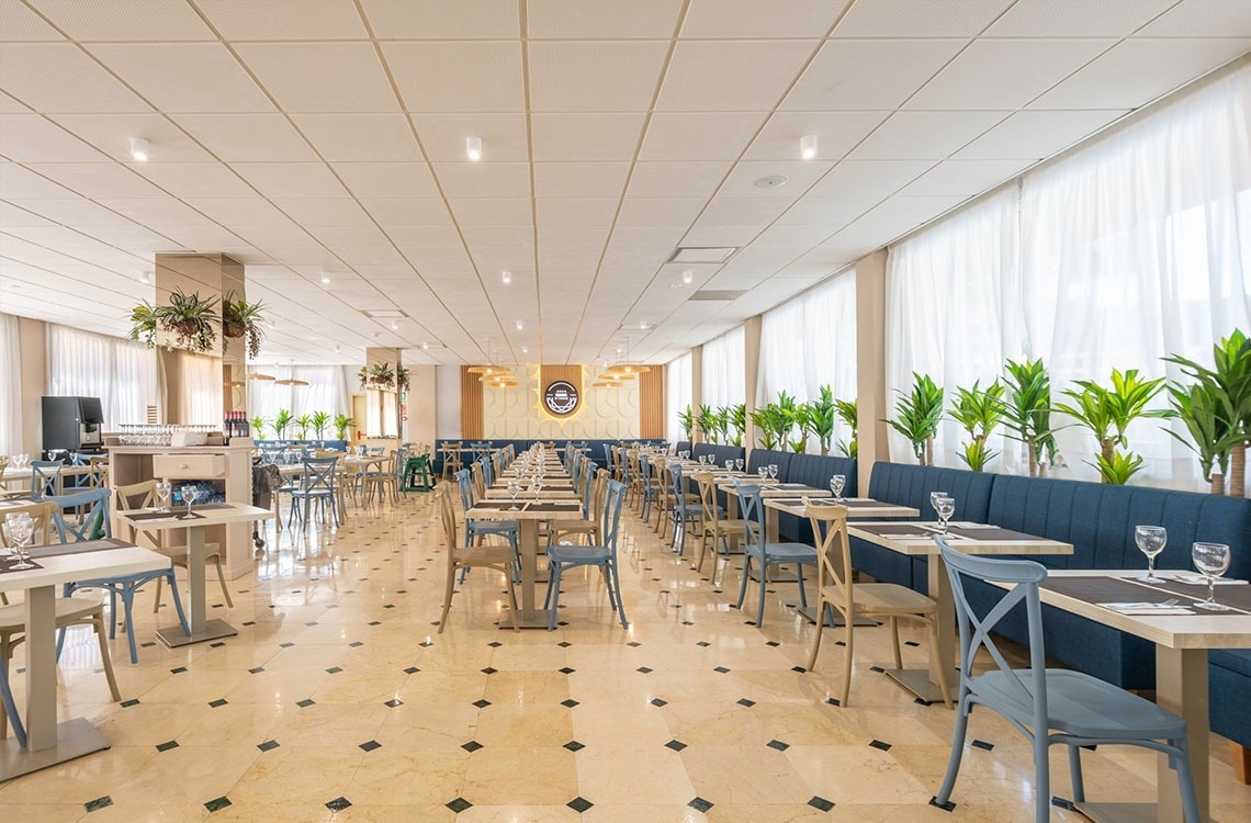 a large dining room with tables and chairs and plants