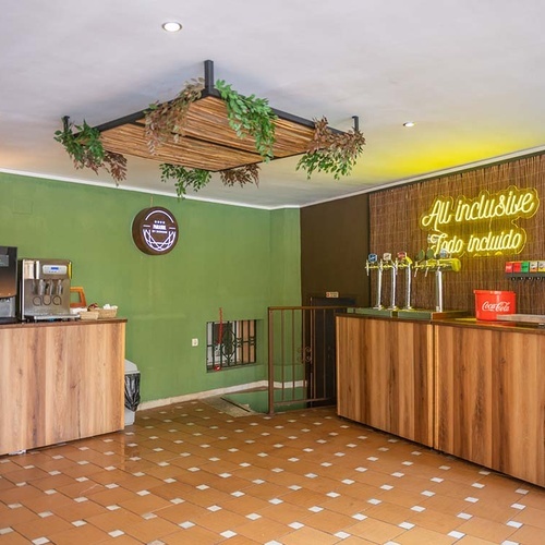 Un área de bar de autoservicio con dispensadores de bebidas variadas, mostradores de madera y un letrero de neón 