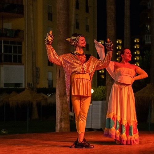 un hombre y una mujer bailan en un escenario por la noche