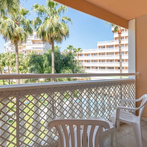 a balcony with a table and chairs and palm trees in the background