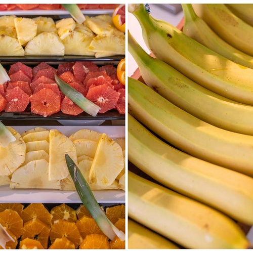 La imagen muestra un variado buffet de frutas frescas, que incluye piña, naranjas sanguinas y naranjas cortadas y decoradas con hojas de piña, al lado de una hilera de plátanos maduros.