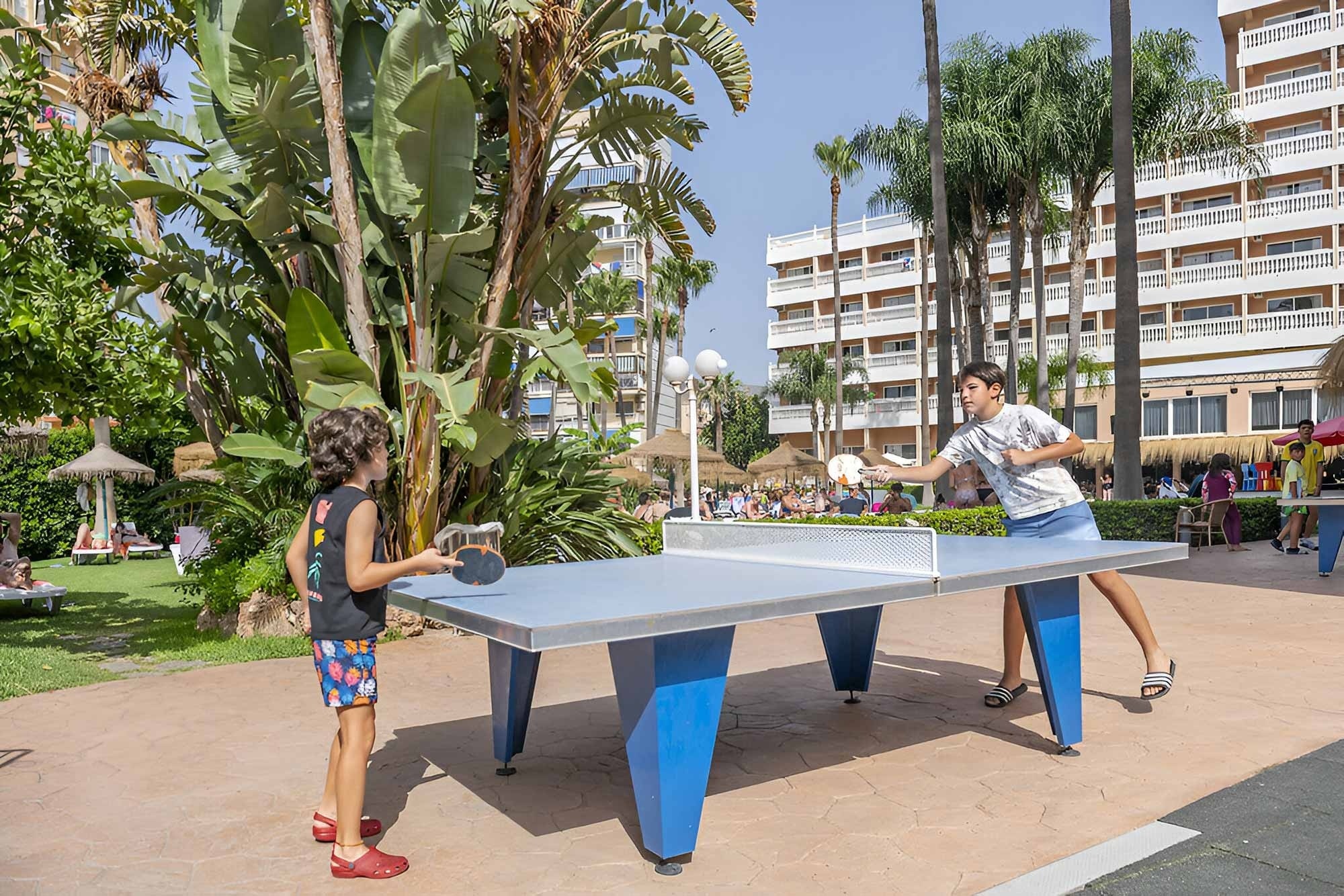 dos niños juegan al tenis de mesa en un parque