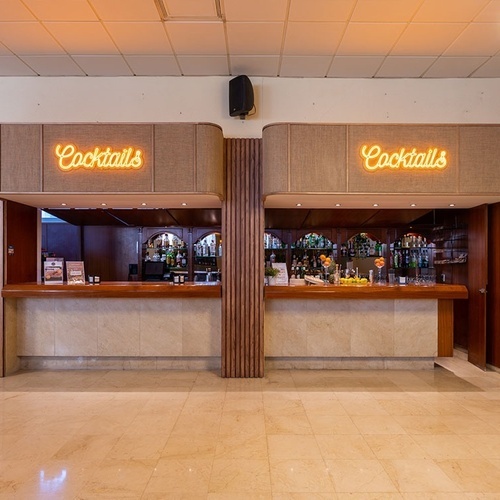 a bar with a neon sign that says cocktails