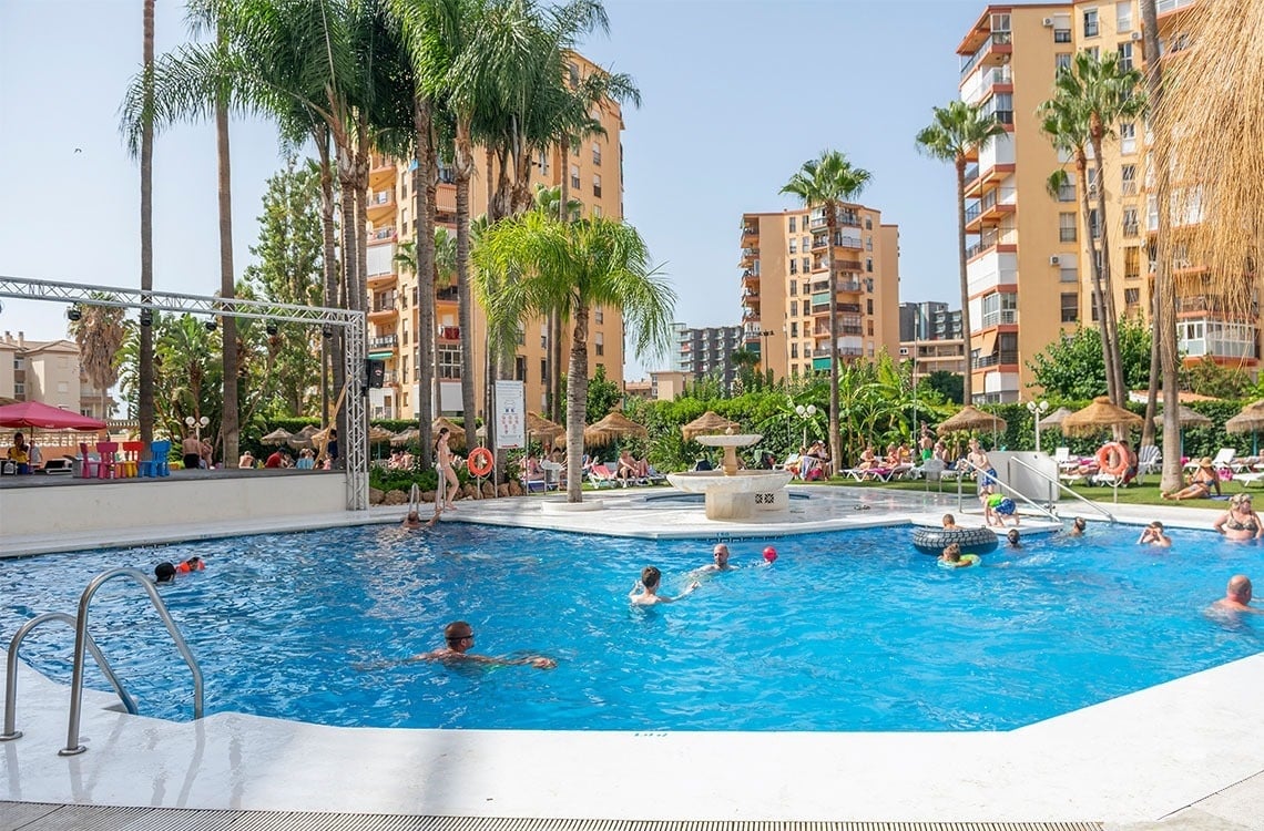 a large swimming pool surrounded by palm trees and buildings