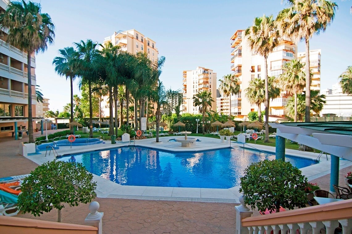 a large swimming pool surrounded by palm trees and buildings