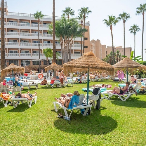 a group of people are laying on the grass in front of a hotel