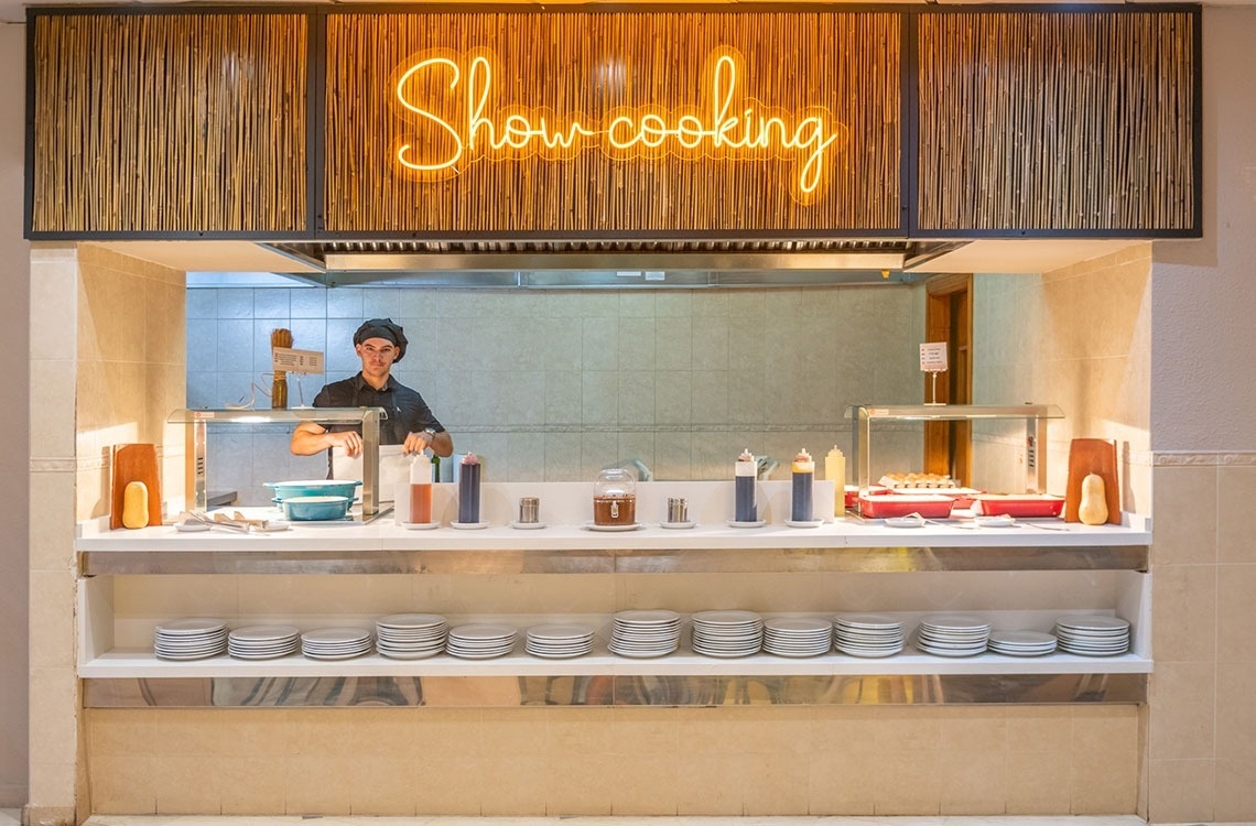 a chef prepares food under a neon sign that says show cooking