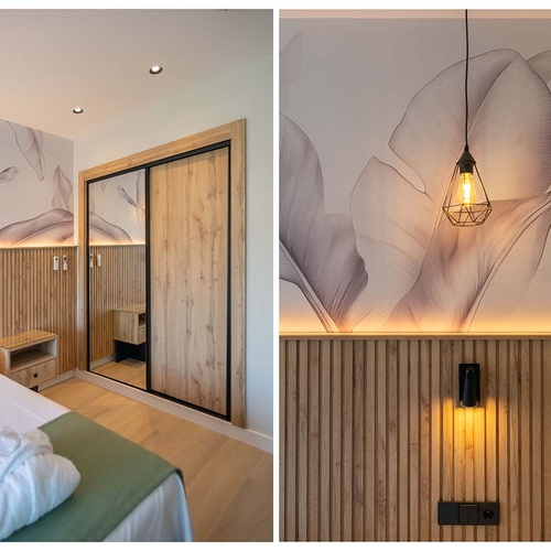 Un dormitorio moderno presenta una pared de acento con lamas de madera y papel tapiz floral, complementado con una iluminación ambiental cálida y un armario con puertas correderas de madera y espejo.