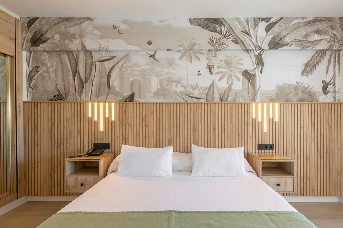 a hotel room with a large mural on the wall above the bed