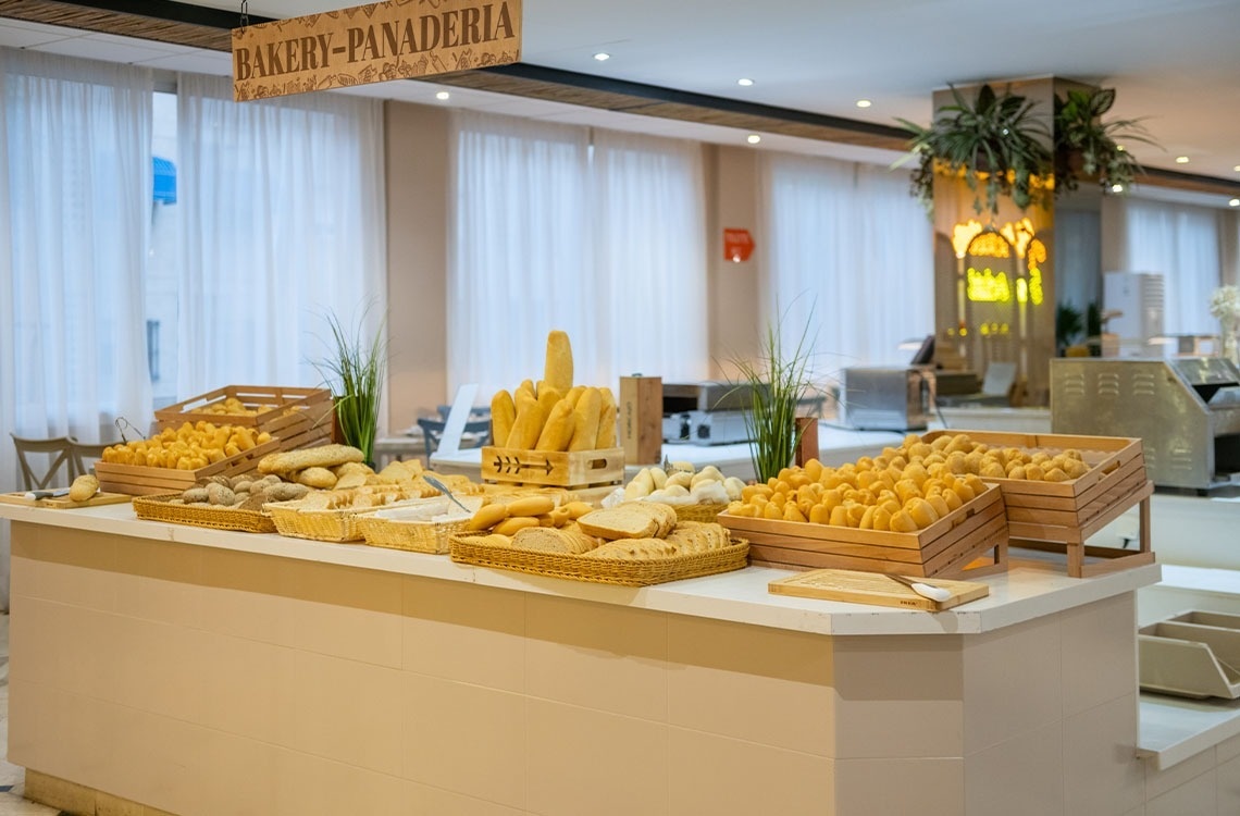 a bakery-panadera sign hangs above a counter full of bread