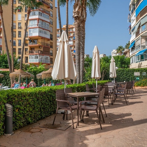 un patio con mesas y sillas y paraguas frente a un edificio