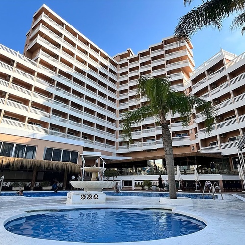 un gran edificio de apartamentos con una piscina al frente