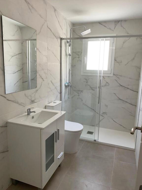 Modern bathroom at Hotel Planas with shower, vanity, and toilet.