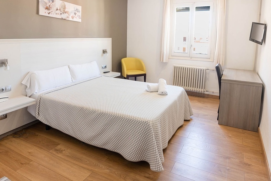 a hotel room with a large bed and a yellow chair