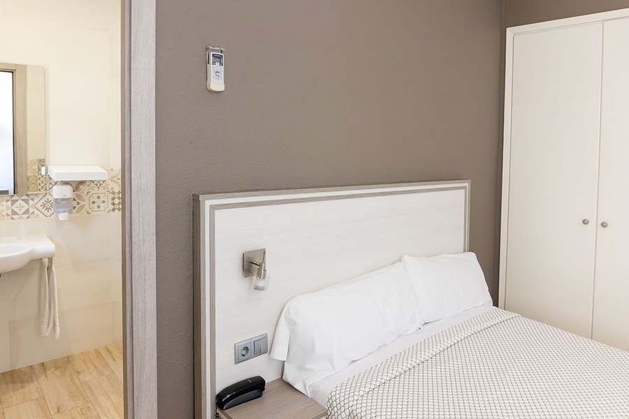 a hotel room with a bed and a remote control on the wall