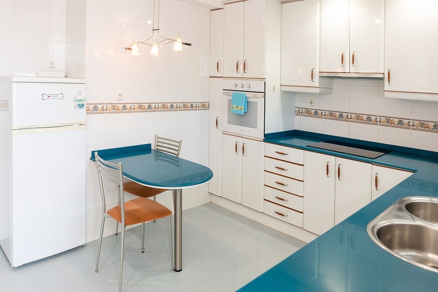 a kitchen with white cabinets and blue counter tops